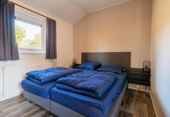 Chambre avec deux lits simples et literie bleue au Velthorst Lodge, De Wije Werelt, Pays-Bas.