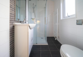 Salle de bain moderne avec douche, toilettes, lavabo et fenêtre à la Velthorst Lodge, De Wije Werelt, Pays-Bas.