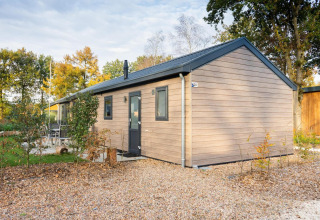 Modern Velthorst lodge at De Wije Werelt in the Netherlands, surrounded by trees and autumn landscape.