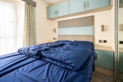 Slaapkamer met blauw donsdeken en moderne inrichting in de Berkel-lodge, De Wije Werelt, Nederland.