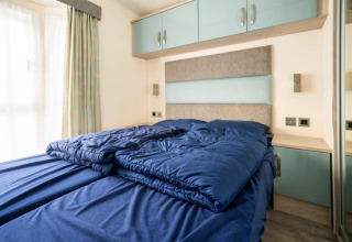 Slaapkamer met blauw donsdeken en moderne inrichting in de Berkel-lodge, De Wije Werelt, Nederland.