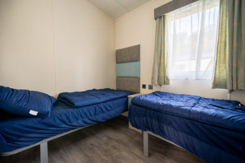 Dos camas individuales con ropa de cama azul en una habitación luminosa de la Berkel lodge, De Wije Werelt, Países Bajos.