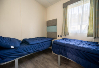 Dos camas individuales con ropa de cama azul en una habitación luminosa de la Berkel lodge, De Wije Werelt, Países Bajos.