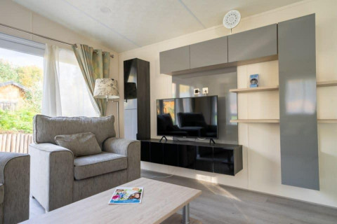 Sala moderna con sofá gris y televisor en la cabaña Berkel de De Wije Werelt, Países Bajos.