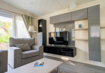 Salon moderne avec canapé gris et télé dans un lodge Berkel à De Wije Werelt, aux Pays-Bas.