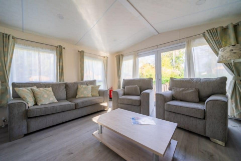 Woonkamer van de Berkel-lodge in De Wije Werelt, Nederland, met grijze zetels en veel daglicht.