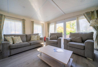 Woonkamer van de Berkel-lodge in De Wije Werelt, Nederland, met grijze zetels en veel daglicht.