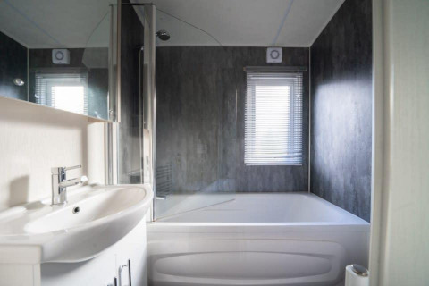Baño moderno en la cabaña Berkel de De Wije Werelt en los Países Bajos, con bañera y lavabo.