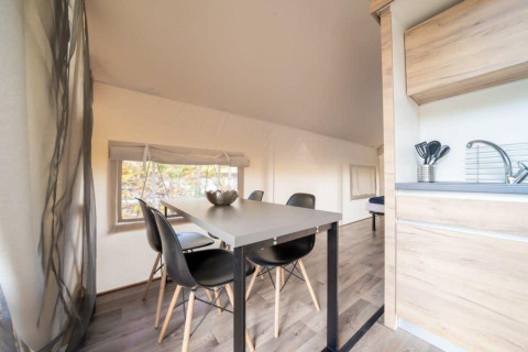 Indvendig udsigt over Glampingtent ved De Wije Werelt i Holland med spisebord og lille køkken.