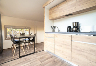 Moderne Küche und Essbereich in einem Glampingtent bei De Wije Werelt, Niederlande, mit Holzmöbeln.