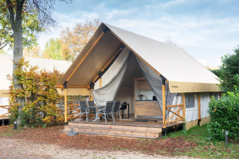 Safari glamping tent at De Wije Werelt in the Netherlands, featuring a wooden deck, dining set and kitchenette.