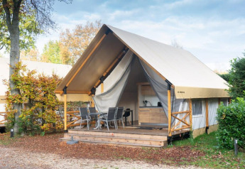 Safari-Glampingzelt bei De Wije Werelt, Niederlande, mit Holzterrasse, Sitzgruppe und moderner Ausstattung.