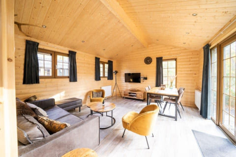 Interior de madera clara en la cabaña Boekhorst de De Wije Werelt, Países Bajos, con muebles modernos y ventanales.
