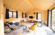 Interior de madera clara en la cabaña Boekhorst de De Wije Werelt, Países Bajos, con muebles modernos y ventanales.