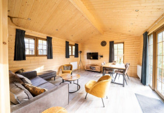 Intérieur en bois clair du lodge Boekhorst à De Wije Werelt, Pays-Bas, avec mobilier moderne et grandes fenêtres.