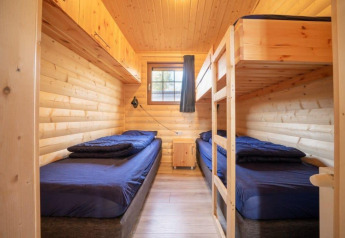 Dormitorio con cuatro camas en una cabaña de madera en Boekhorst, De Wije Werelt, Países Bajos, luz natural.