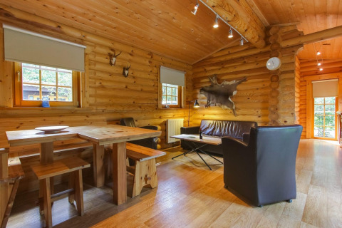 Sfeervol houten interieur van lodge Boekhorst in De Wije Werelt, Nederland, met eet- en zithoek.