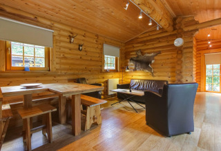 Sfeervol houten interieur van lodge Boekhorst in De Wije Werelt, Nederland, met eet- en zithoek.
