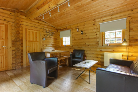 Knus interieur van Boekhorst lodge op De Wije Werelt in Nederland, met leren stoelen en houten decor.