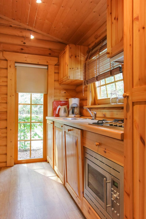 Cocina de madera en la cabaña Boekhorst de De Wije Werelt, Países Bajos, con electrodomésticos y luz natural.