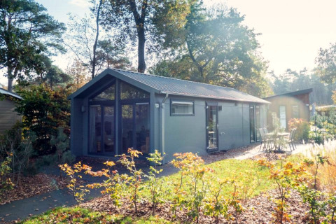 Modern Berkel lodge nestled in a scenic forest setting with large windows and outdoor seating area.