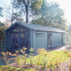 Moderne lodge Berkel i en grøn skovomgivelse, med store vinduer og udendørs siddeplads i solen.