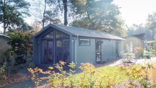 Lodge moderne Berkel situé en pleine forêt, grandes baies vitrées et terrasse extérieure ensoleillée.