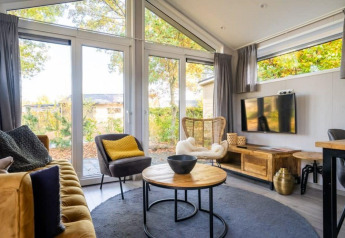 Bright lodge interior at Berkel, De Wije Werelt, Netherlands, featuring modern decor and large windows to nature.