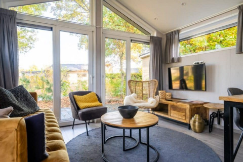 Intérieur lumineux du lodge Berkel à De Wije Werelt, Pays-Bas, avec de grandes fenêtres et une décoration moderne.