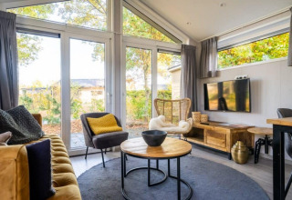 Intérieur lumineux du lodge Berkel à De Wije Werelt, Pays-Bas, avec de grandes fenêtres et une décoration moderne.