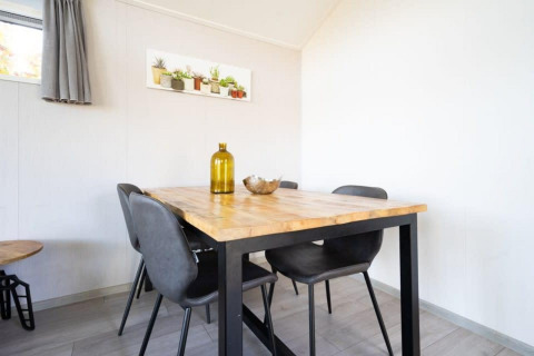 Salle à manger lumineuse avec table en bois, chaises noires et déco, dans le lodge Berkel à De Wije Werelt.