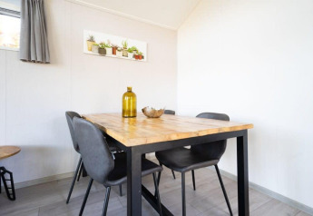 Comedor luminoso con mesa de madera, sillas negras y decoración en la cabaña Berkel de De Wije Werelt.