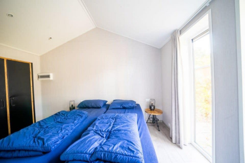 Dormitorio en la cabaña Berkel en De Wije Werelt, Países Bajos, con dos camas individuales y ropa azul.