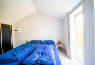 Dormitorio en la cabaña Berkel en De Wije Werelt, Países Bajos, con dos camas individuales y ropa azul.