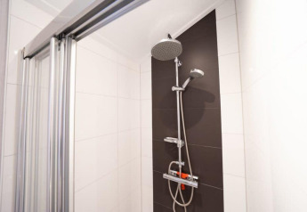 Shower in modern bathroom at Berkel, De Wije Werelt lodge, featuring glass door and dark accent wall, Netherlands.