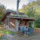 Foto af Nature Lodge, en hyggelig træhytte med terrasse, udendørs spisebord og omgivet af frodig skov.