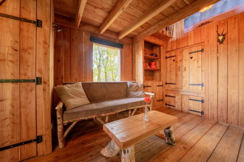 Knusse houten lodge met rustieke bank en tafel in Nature Lodge op De Wije Werelt, Nederland.