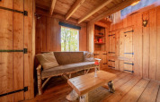Acogedora cabaña de madera con sofá rústico y mesa en Nature Lodge de De Wije Werelt, Países Bajos.