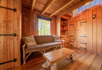 Cabane en bois chaleureuse avec canapé rustique et table au Nature Lodge, De Wije Werelt, Pays-Bas.