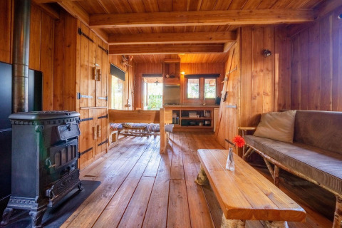 Houten interieur van Nature Lodge bij De Wije Werelt in Nederland met houtkachel en rustieke bank.