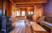 Houten interieur van Nature Lodge bij De Wije Werelt in Nederland, met kachel en rustieke zitbank.