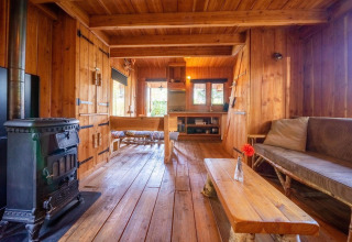 Interior de madera de Nature Lodge en De Wije Werelt, Países Bajos, con estufa y muebles rústicos.