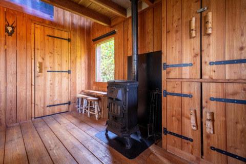 Intérieur en bois avec poêle, armoires et fenêtre à la Nature Lodge de De Wije Werelt, Pays-Bas.