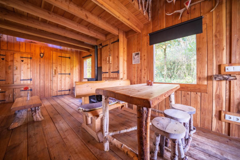 Interieur van Nature Lodge bij De Wije Werelt in Nederland met houten meubels en uitzicht op het bos.