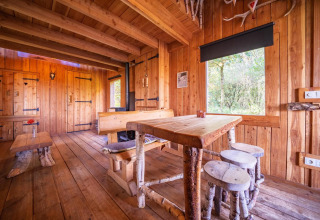 Interior de Nature Lodge en De Wije Werelt, Países Bajos, con muebles de madera y vista al bosque.