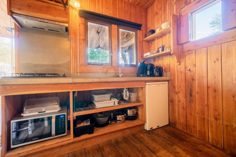 Keuken in Nature Lodge, De Wije Werelt, Nederland, met houten wanden en diverse apparatuur.