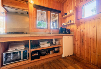 Kitchen area inside Nature Lodge, De Wije Werelt, Netherlands, with wooden walls and appliances.