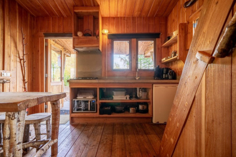 Houten interieur van Nature Lodge op De Wije Werelt in Nederland, met rustieke keuken en eetgedeelte.