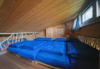 Loftsoveværelse i Nature Lodge ved De Wije Werelt i Holland, med træpaneler og store blå sengetæpper.