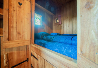 Alcôve en bois avec literie bleue, fenêtres, à la Nature Lodge de De Wije Werelt, Pays-Bas.
